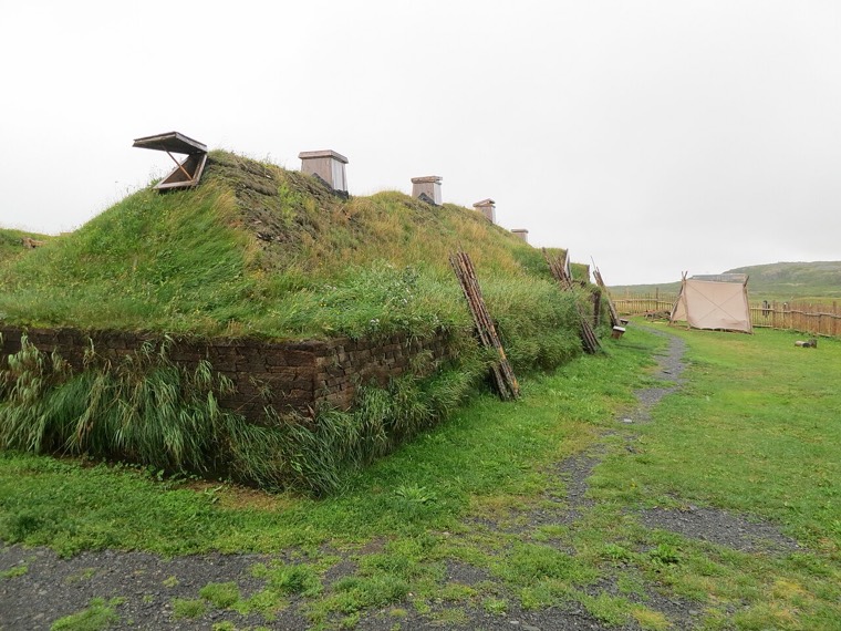 Low turf-walled halls with grass roofs, reconstructed on the open coastal ground of L’Anse aux Meadows, Newfoundland.